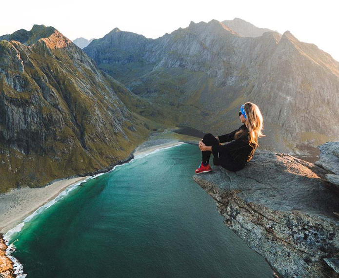 A woman sitting on top of a mountain next to a lake