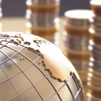 A close up of a globe with stacks of coins in the background